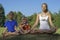 Mother with kids meditating on green grass