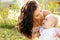 Mother kissing her dear baby, outdoors portrait