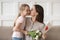 Mother kissing little daughter express gratitude for flowers and postcard