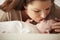 Mother Kissing Newborn Baby Lying On Changing Table In Nursery