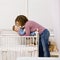 Mother laying son down into crib