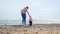 A mother leads the baby by the arm to the sea. Outdoor walks. Real time.