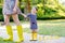 Mother and little adorable toddler child in yellow rubber boots, family look, in summer park. Beautiful woman and cute