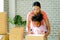 Mother and little American African girl help together to set or pack paper box or carton during move to new house, they look happy