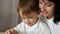 A mother and a little boy are looking intently at the tablet screen. A mother plays with her child using an app over the