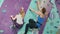 Mother and little child climbing in rock-climbing center wearing safety gear