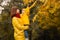 Mother and little daughter admire a beautiful tree with yellow autumn leaves. Happy family concept