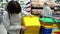 Mother and little daughter choose plastic container for toys in supermarket.