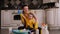 A mother and little daughter are cleaning, sitting on the floor among detergents