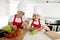 Mother and little daughter cooking together with hat apron preparing salad at home kitchen