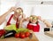 Mother and little daughter cooking together playing with cucumber slices on the eyes