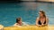 The mother with little daughter have fun in the pool. Mom plays with the child. The family enjoy summer vacation in a