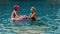 The mother with little daughter have fun in the pool. Mom plays with the child. The family enjoy summer vacation in a