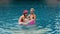 The mother with little daughter have fun in the pool. Mom plays with the child. The family enjoy summer vacation in a