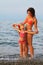 Mother and little daughter standing on beach