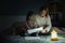 Mother and little daughter studying and drawing in a complete darkness during electricity outage. Little girl uses camping lantern