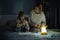 Mother and little daughter studying and drawing in a complete darkness during electricity outage. Little girl uses camping lantern