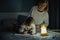 Mother and little daughter studying and drawing in a complete darkness during electricity outage. Little girl uses camping lantern