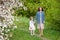 Mother and little daughter walking in blooming apple garden. Mom loves her child. Spring story. Happy family in beautiful spring