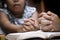 Mother and little girl hands folded in prayer on a Holy Bible