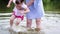 Mother of the little girl washes his feet in the river. Woman playing with her baby on the beach