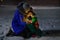 Mother and little son with lantern sitting on the street in winter evening