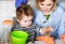 Mother and little son planting flower. Spring house gardening. Cute boy helps mom to care for plants.