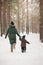 Mother and little toddler boy walking in the winter forest and having fun with snow. Family enjoying winter