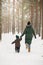 Mother and little toddler boy walking in the winter forest and having fun with snow. Family enjoying winter. Child and woman