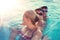 Mother looking back to smiling sons in swimming pool