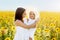 A mother lovingly looks at her daughter at sunset in a field of sunflowers. Happy family. Unity with nature