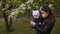 A mother in a medical mask holds a one-year-old child in a Park in a springtime.