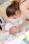 A mother in a medical protective mask takes care of her baby at home in a corontine. Prophylactic protection of coronavirus and