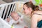 A mother in a medical protective mask takes care of her baby at home in a corontine. Prophylactic protection of coronavirus and