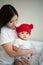 Mother and newborn baby wearing red hats In the white bedroom, warm sunlight in the evening of the day