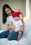 Mother and newborn baby wearing red hats In the white bedroom, warm sunlight in the evening of the day