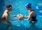 Mother and newborn child at infant swimming class. Female instructor carrying out swimming lessons for parent and baby