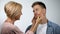 Mother pinching unhappy son cheeks, overprotective parenting style, problem