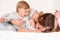 Mother play with her daughter on white bed background
