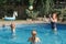 Mother playing ball with daughters children in swimming pool on home backyard. Mom and sisters siblings having fun in swimming