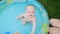 Mother playing with her 1 year old baby boy swimming in inflatable pool