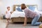 Mother is playing peek a boo or hide and seek with her little baby toddler in the bedroom while the girl is laughing in happiness