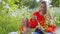 mother plays with her daughter sitting in grass in field blowing soap bubbles