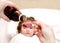 Mother pouring medication in a spoon in the foreground and sick