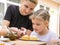 Mother pours bag of confectionery posypku on Easter cupcake, daughter happily looking