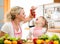 Mother preparing dinner and feeding kid tomatoes in kitchen