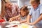 Mother preparing pizza with kids