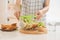 Mother preparing sandwich for school lunch on table