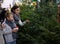 Mother and preteen son choosing New Year fir tree on outdoor fair