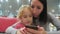 Mother and pretty daughter sitting at cafe and looking at smartphone.